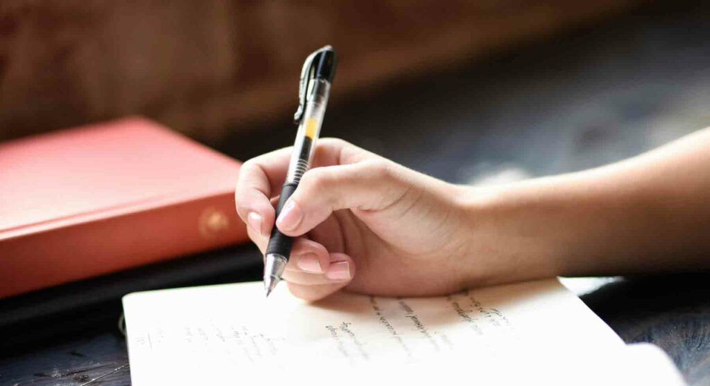 Main tenant un stylo, posée sur une feuille